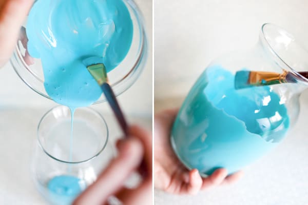 Hands painting a vase with blue paint. 