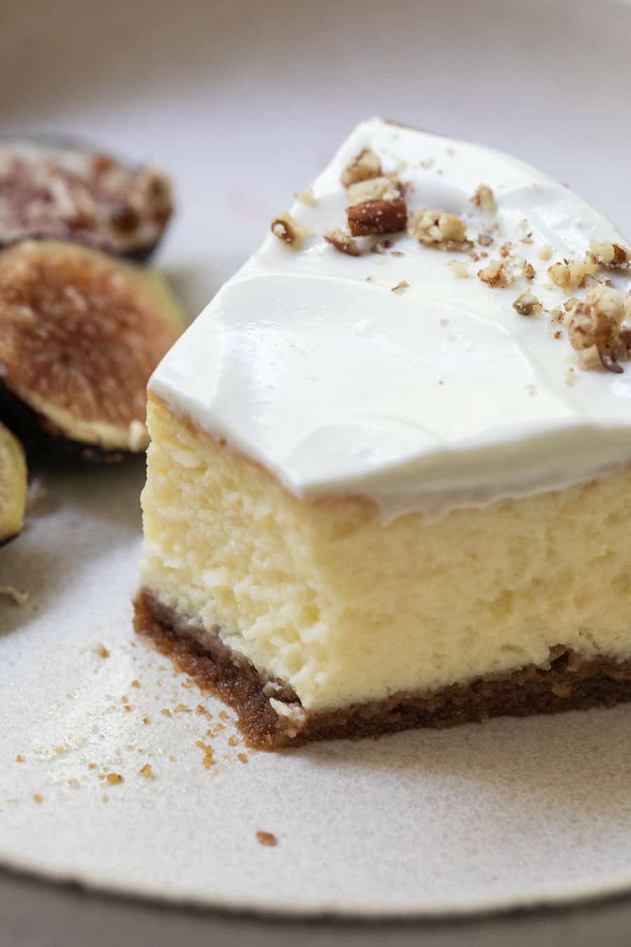 Slice of cheesecake with sour cream frosting and walnuts.