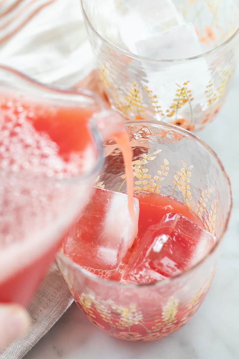 red juice pouring into a glass filled with ice.