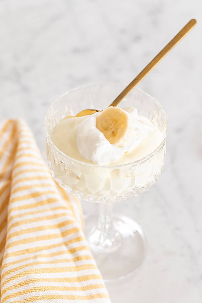 Banana pudding with a yellow striped towel and gold spoon.