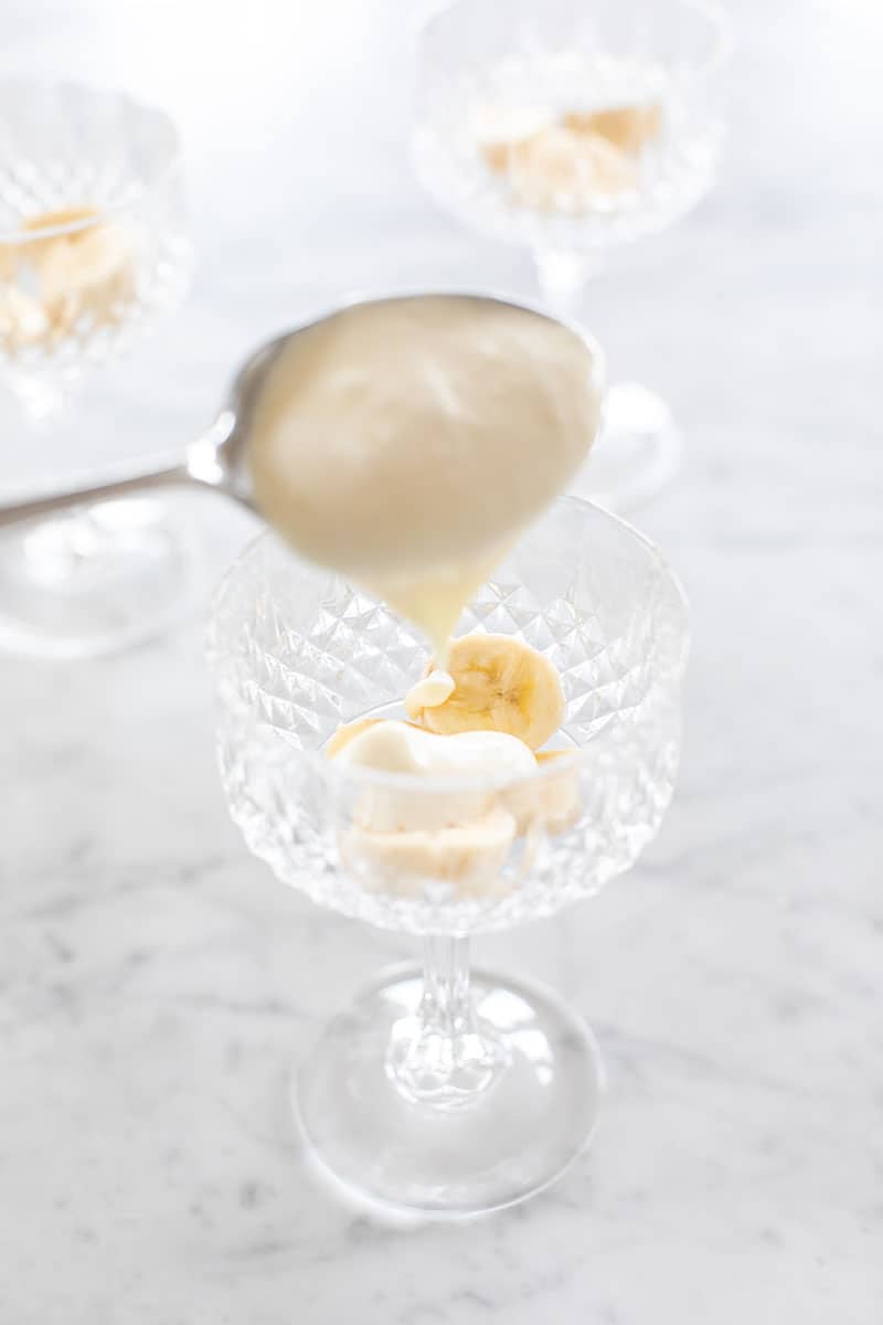 Scooping banana pudding into a small glass. 