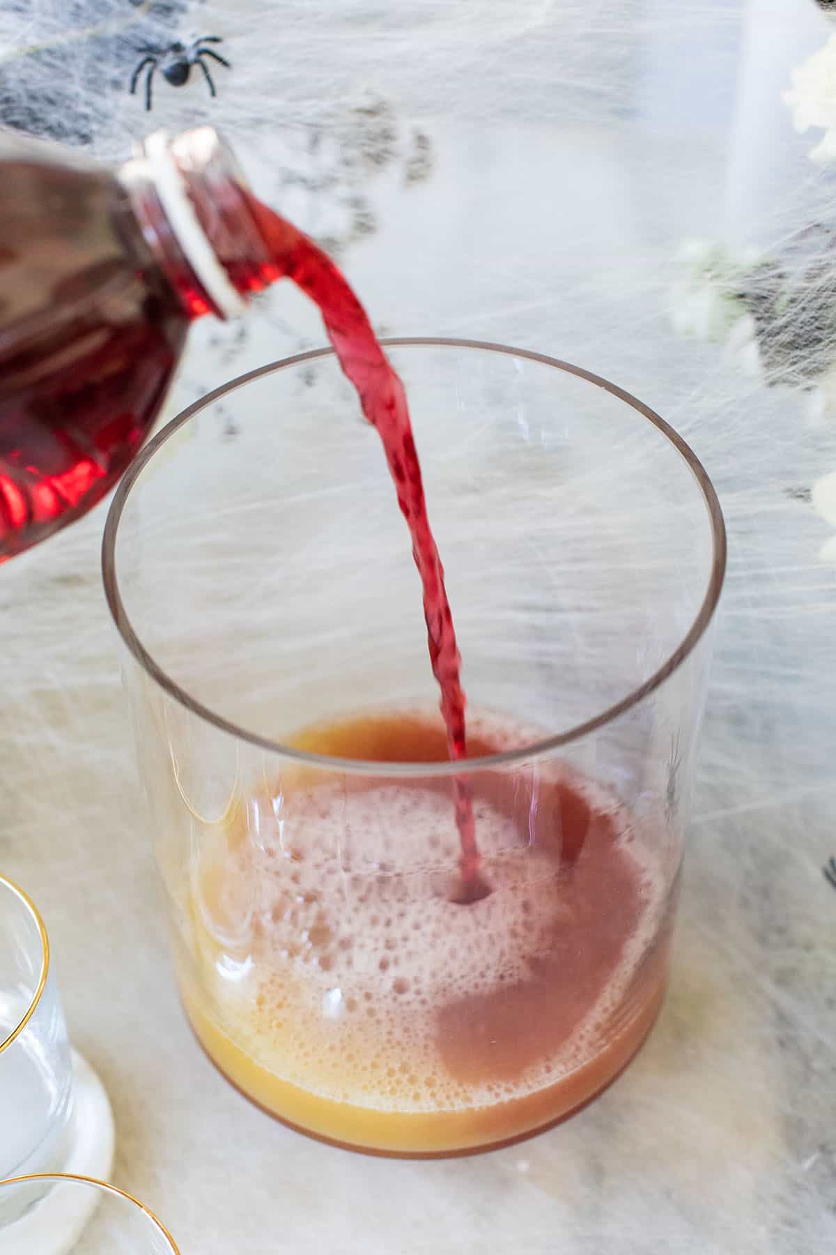 Pouring juice into a punch bowl to make Jolly Rancher punch for Halloween.