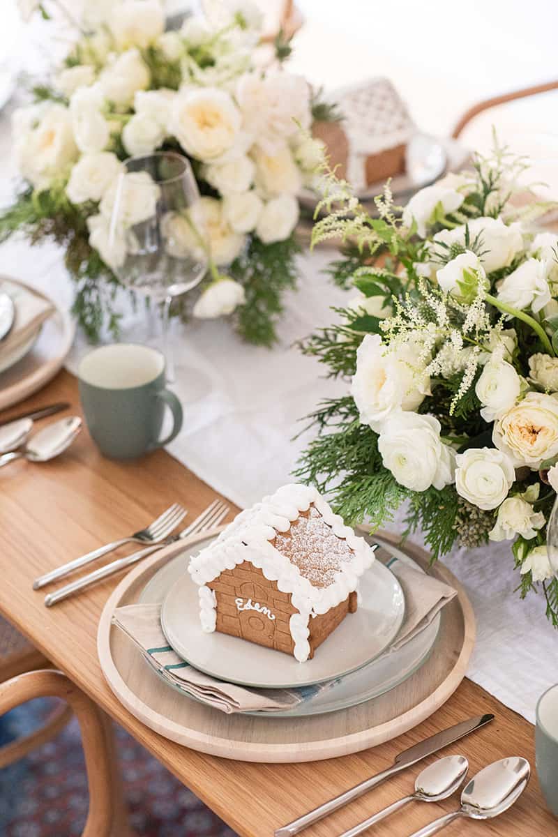 Gingerbread house on a table with white flowers 