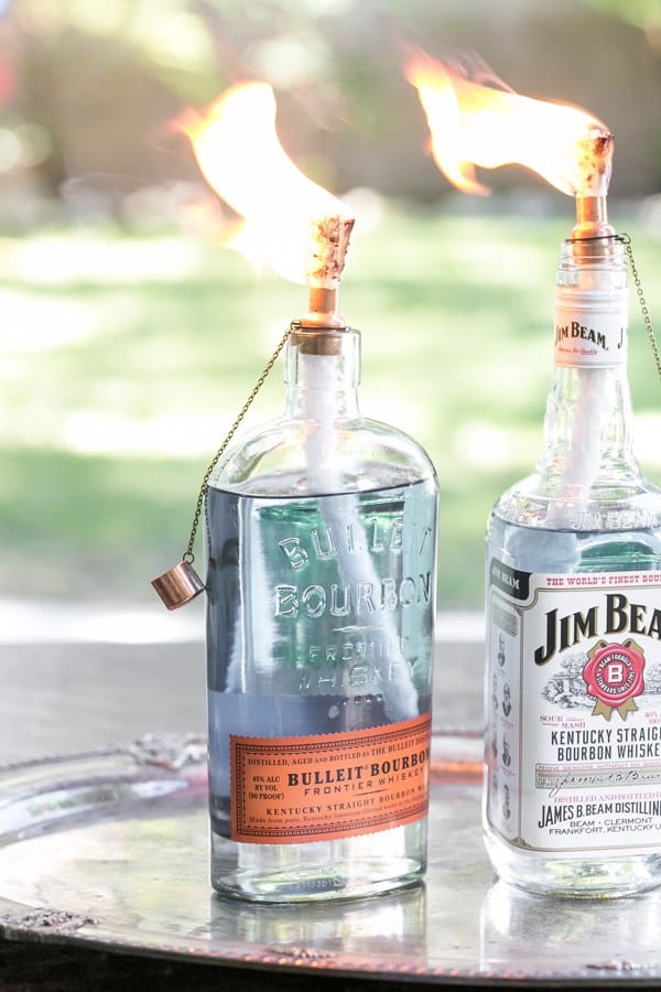 Glass bourbon and Jim Beam bottles with tiki torch hardware and fire.