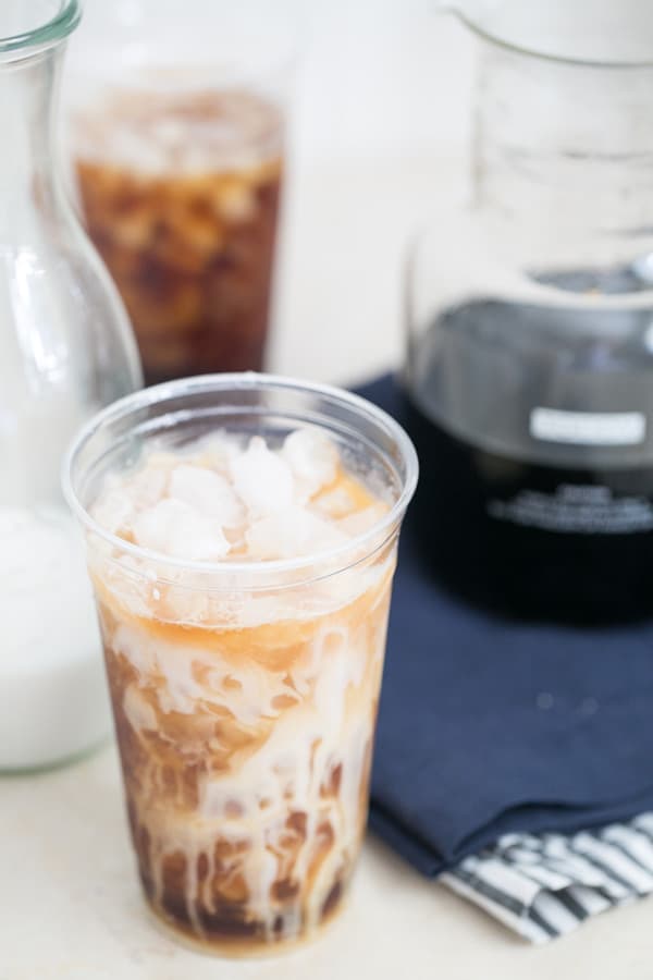 Cup filled with iced coffee and almond milk.