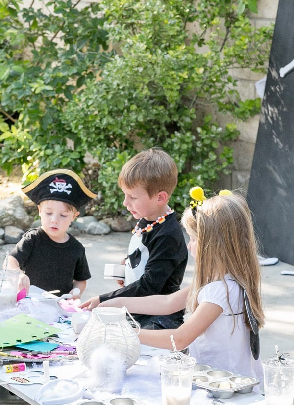 shot of kids around a table playing with kids halloween party ideas