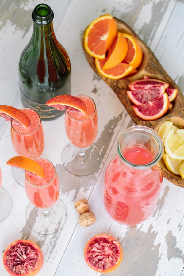 Overhead of mimosas on wood table with blood oranges.