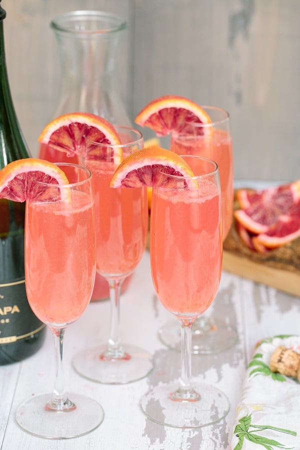 Four glasses pink mimosas on wooden board. 