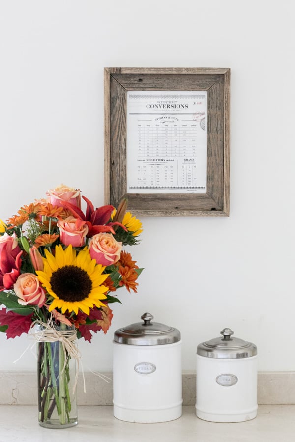 kitchen conversion chart framed in wooden frame with flowers.