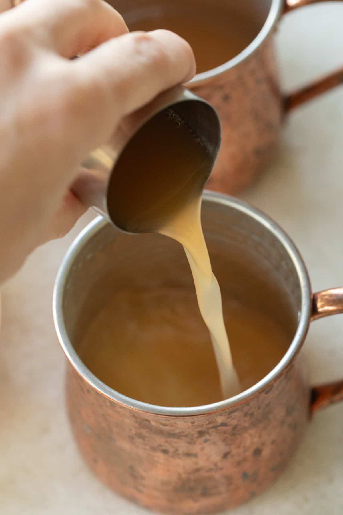 Pouring apple cider into a copper mug. 