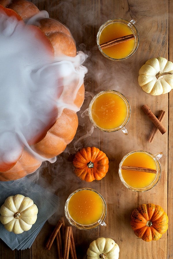 Pumpkin punch in cups with mini pumpkins and a large smoking pumpkin.