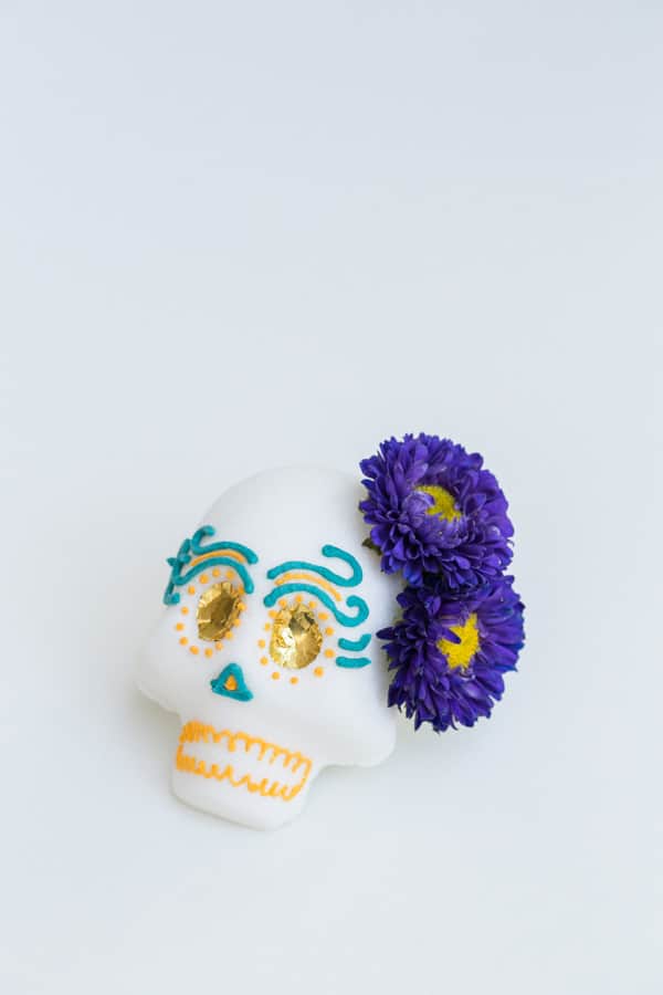 finished project shot of a Mexican sugar skull with purple flowers and gold foil eyes.