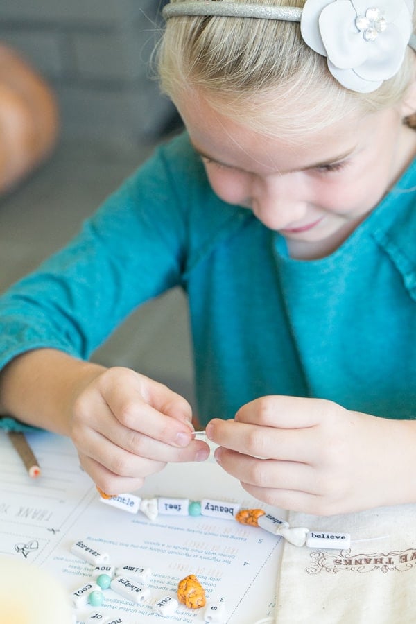 Girl stringing a Thanksgiving craft necklace for kids.