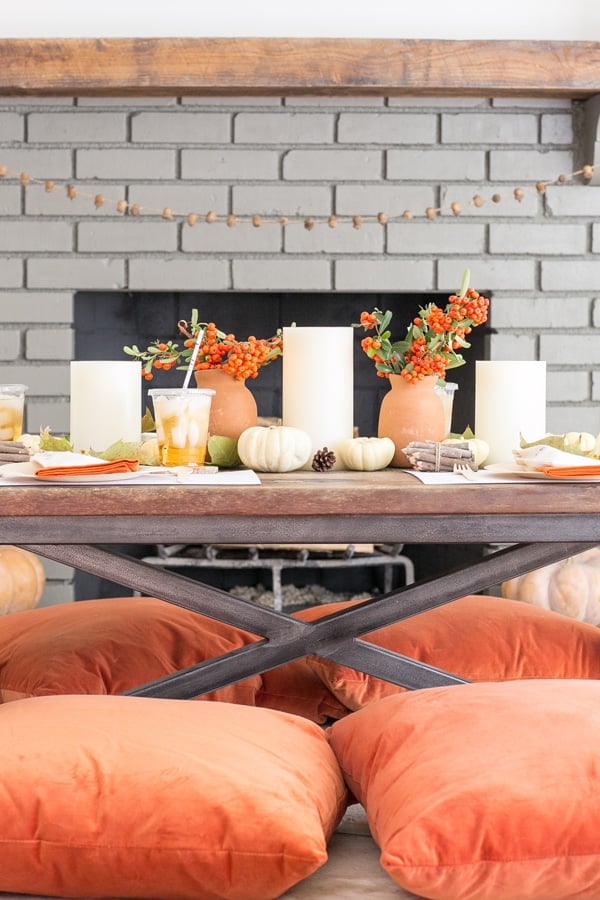 Thanksgiving table set for kids with orange pillows, flowers, games, crafts and more!