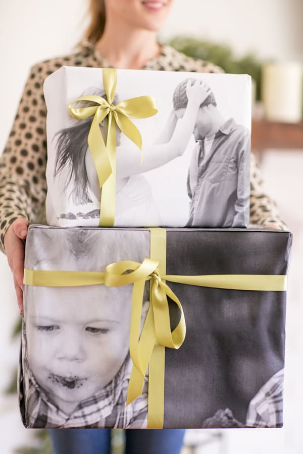 Eden Passante holding two photo print wrapping presents with green bows. 