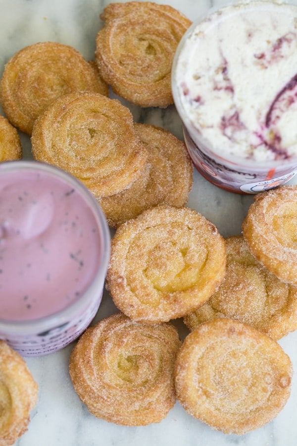 Homemade churros on a marble table with tubs of ice cream.