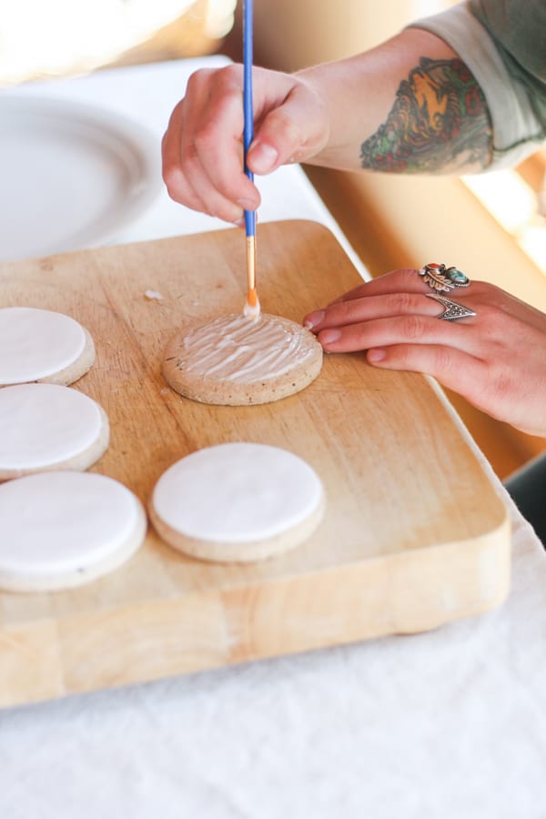 Painting royal icing on a cookie to glue fondant for painted cookies.