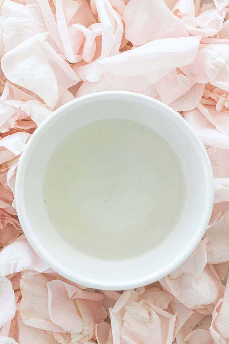 Bowl of rose water with pink rose petals.
