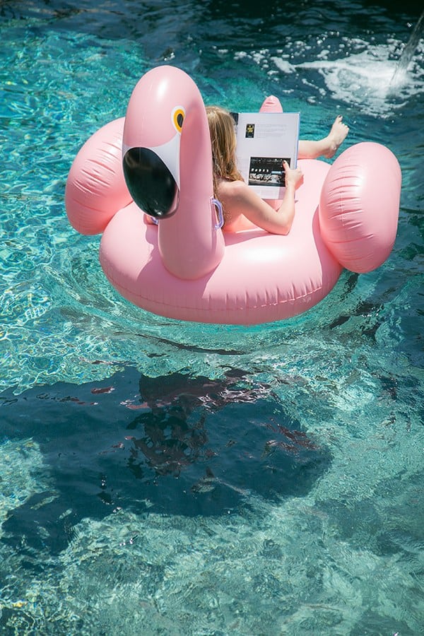 Girl floating on a pink flamingo pool float at a flamingo pool party 