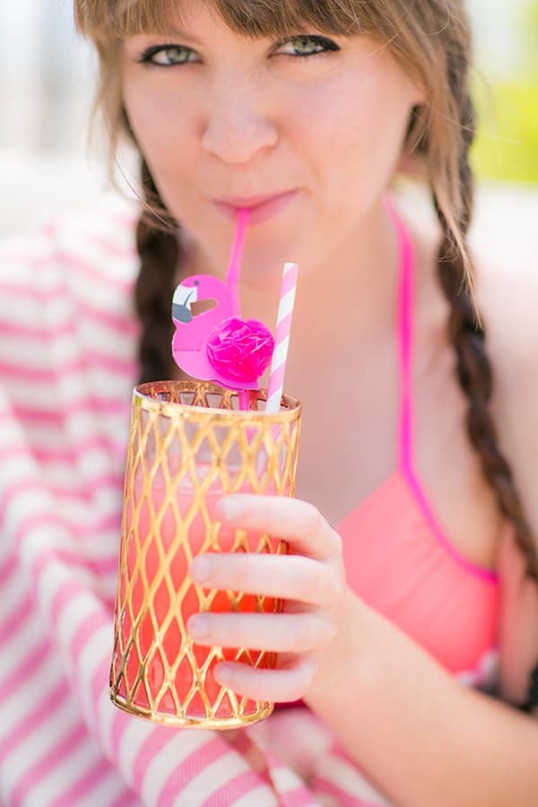 Girl sipping a cocktail out of a flamingo straw at a flamingo pool party 