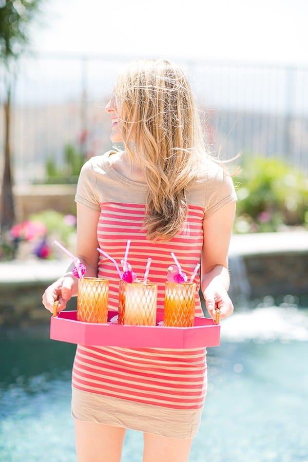 Eden Passante holding a tray of cocktails at a flamingo pool party 