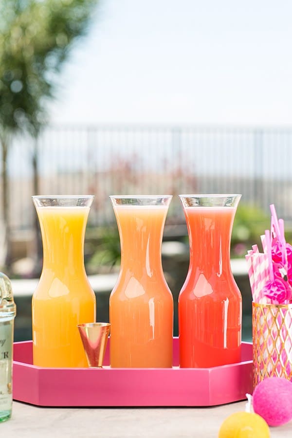 three fresh juices on a pink tray