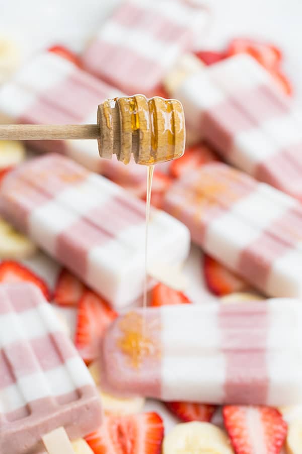 Honey drizzled over the top of strawberry banana popsicles. 