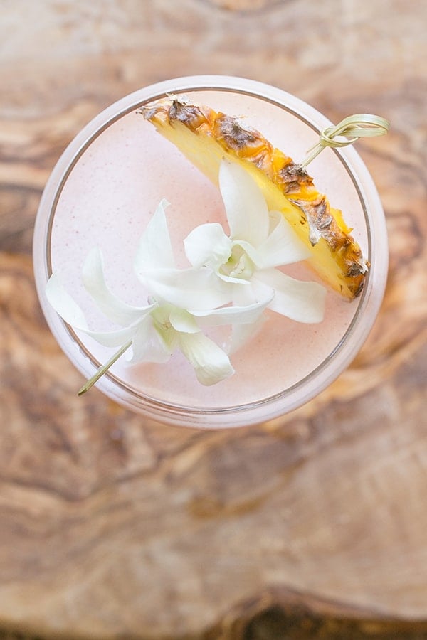 Tiki drink recipe with pineapple and flowers.