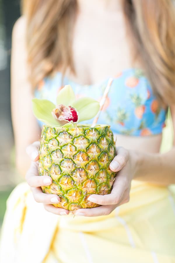 Girl holding a pineapple cocktail.