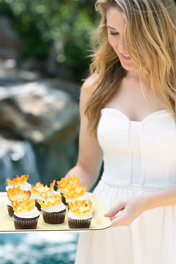 Eden Passante holding a yellow tray with pineapple cupcakes.