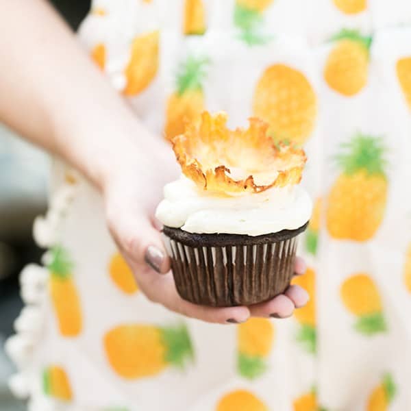 Hand holding a pineapple cupcake.