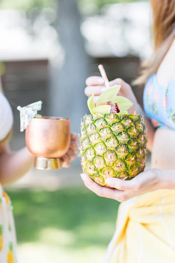 Two girls holding a pineapple mojito and a pineapple Moscow mule