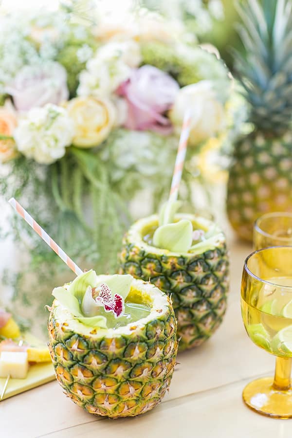 Two pineapples with pineapple mojito inside and straws.