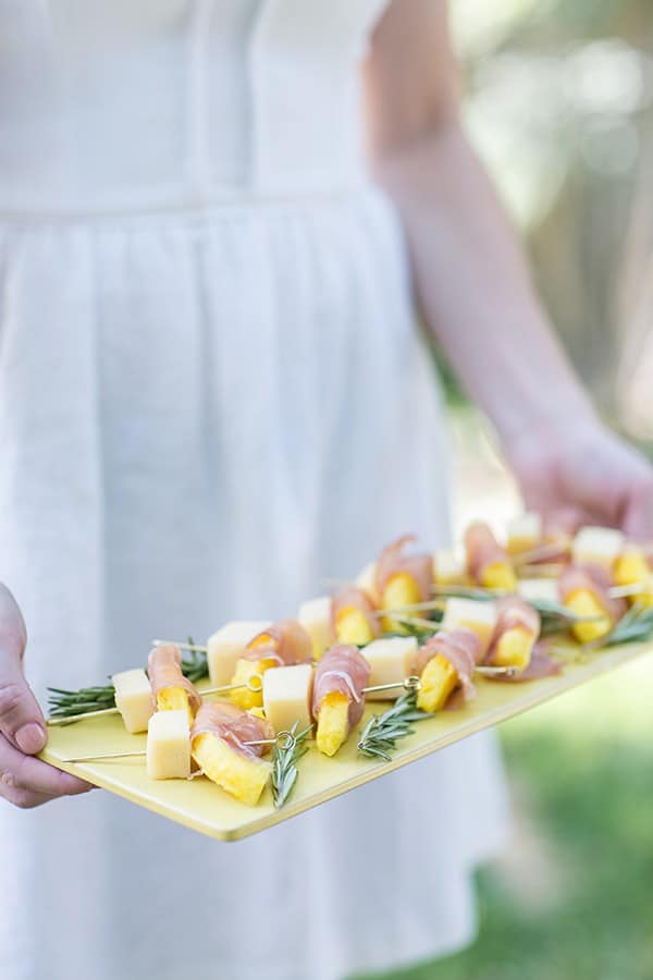 Pineapple wrapped in prosciutto on a yellow plate.