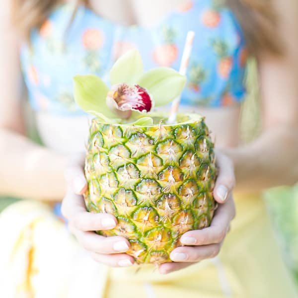 Girl holding a fresh pineapple cocktail.