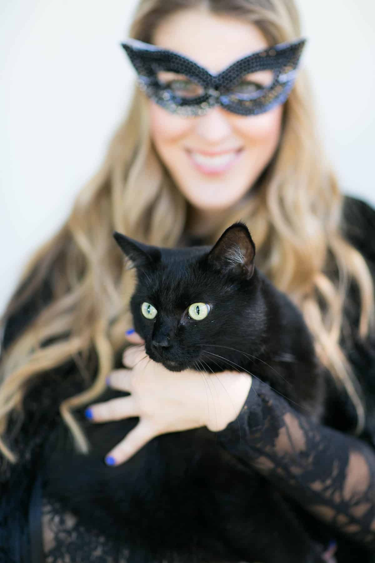 holding a black cat at a Halloween party 