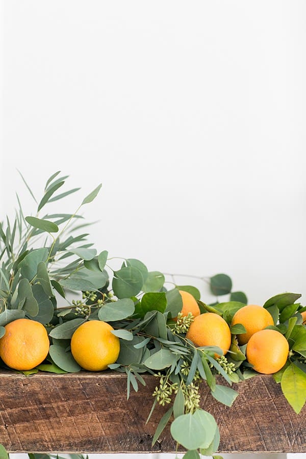 Green garland with oranges on a mantle.