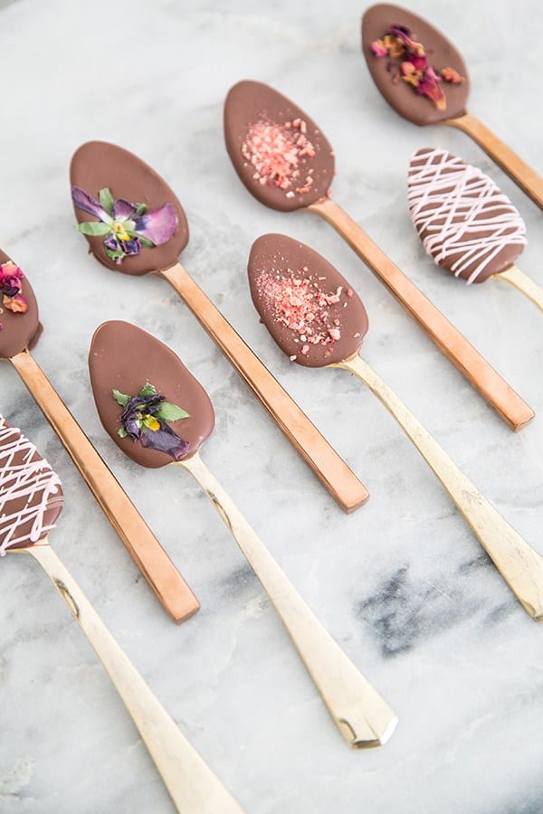 chocolate spoons with flowers, crushed raspberries and white chocolate designs.