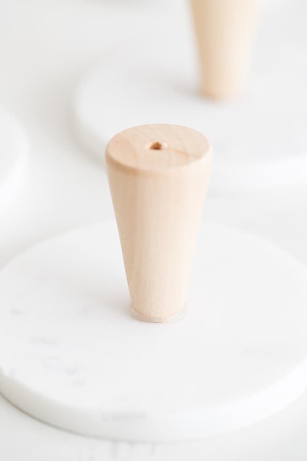 wooden dowel being glued to a marble coaster for a mini cake stand