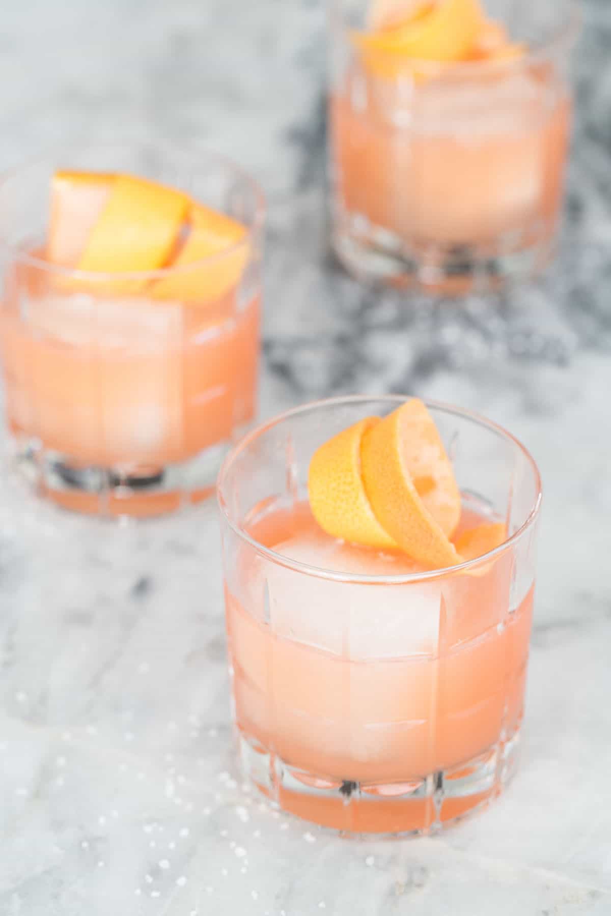 three grapefruit and tequila cocktails with orange rind