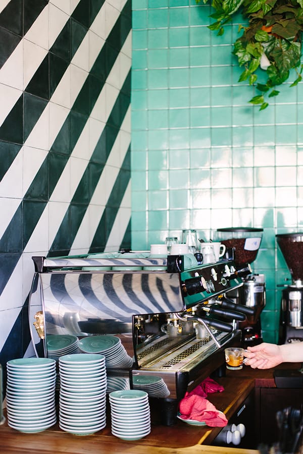 Espresso machine with coffee and green and black and white tile.