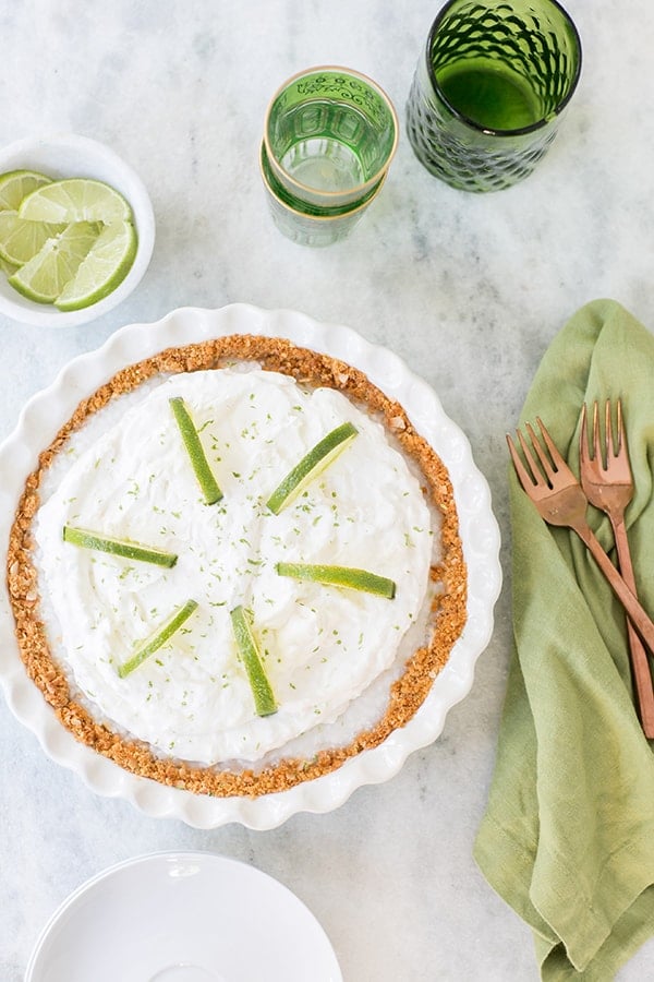 Key lime pie with whipped cream, limes on a table