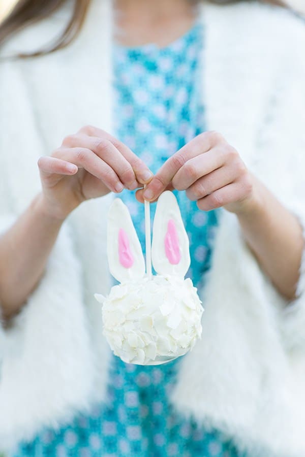 Girl holding a candy apple made into an Easter bunny.