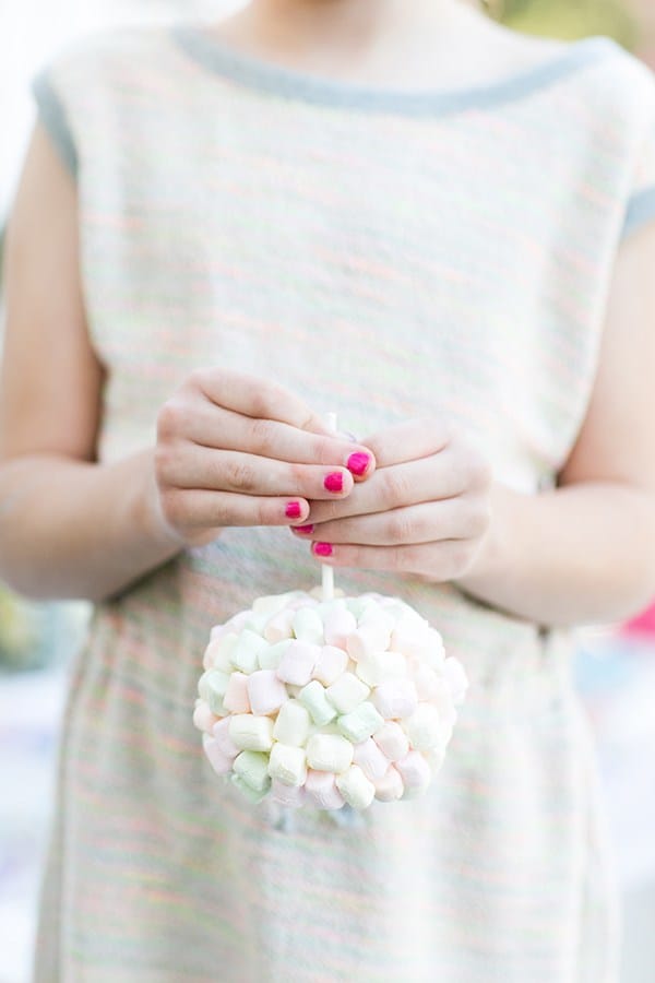 Girl holding a candy apple topped with marshmallows.