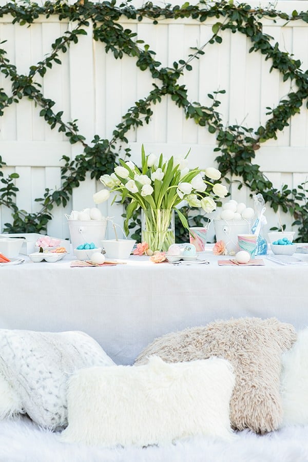 Easter party for kids with a table, flowers and throw pillows.