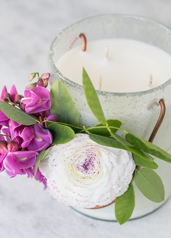 An essential oil candle decorated with fresh flowers.