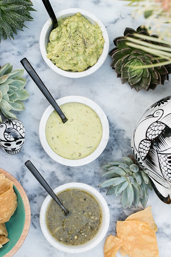 Three salsas in marble bowls with black spoons.