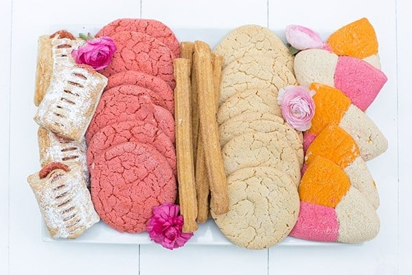 Colorful Mexican cookies and churros on a white platter.