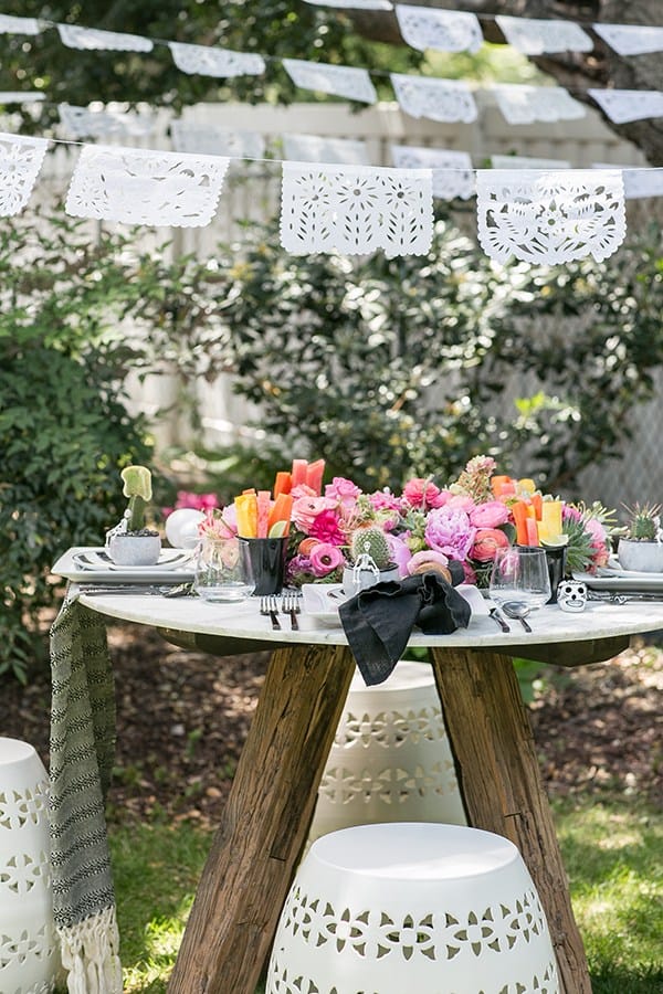 Cinco de Mayo table setting with pink flowers, fruit and benches.