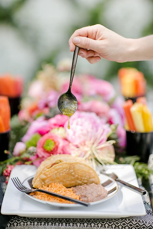 Black spoon with salsa pouring onto a taco for Cinco de Mayo